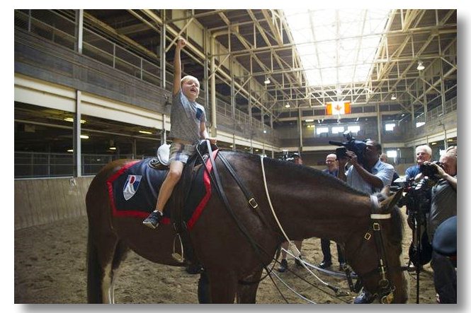 Nolan Russell, then 7, punches the air in happiness after mounting the Clydesdale named Russell in honor of his father, who died on duty in 2011. June 21, 2016. - Chris So/Toronto Star